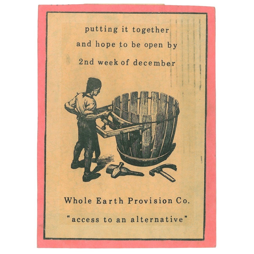 The first ever Whole Earth Provision Co. ad features man assembling a barrel with text that reads "Putting it together and hoping to be open by 2nd week of December. At the bottom, the company's name is spelled out with the phrase "Access to an Alternative" typed in quotes